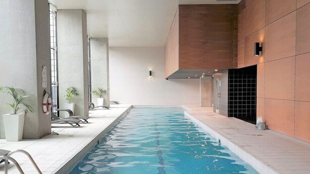 An indoor swimming pool with clear water, surrounded by tiled walls and a few potted plants. - Stunning City View 2BR in CBD by Readyset Apartments (Melbourne)