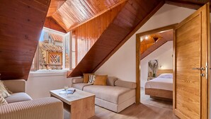 A cozy loft bedroom with a sloped ceiling, wooden beams, a bed, a sofa, and a small table. - Hedera Estate, Hedera A6 (Dubrovnik)