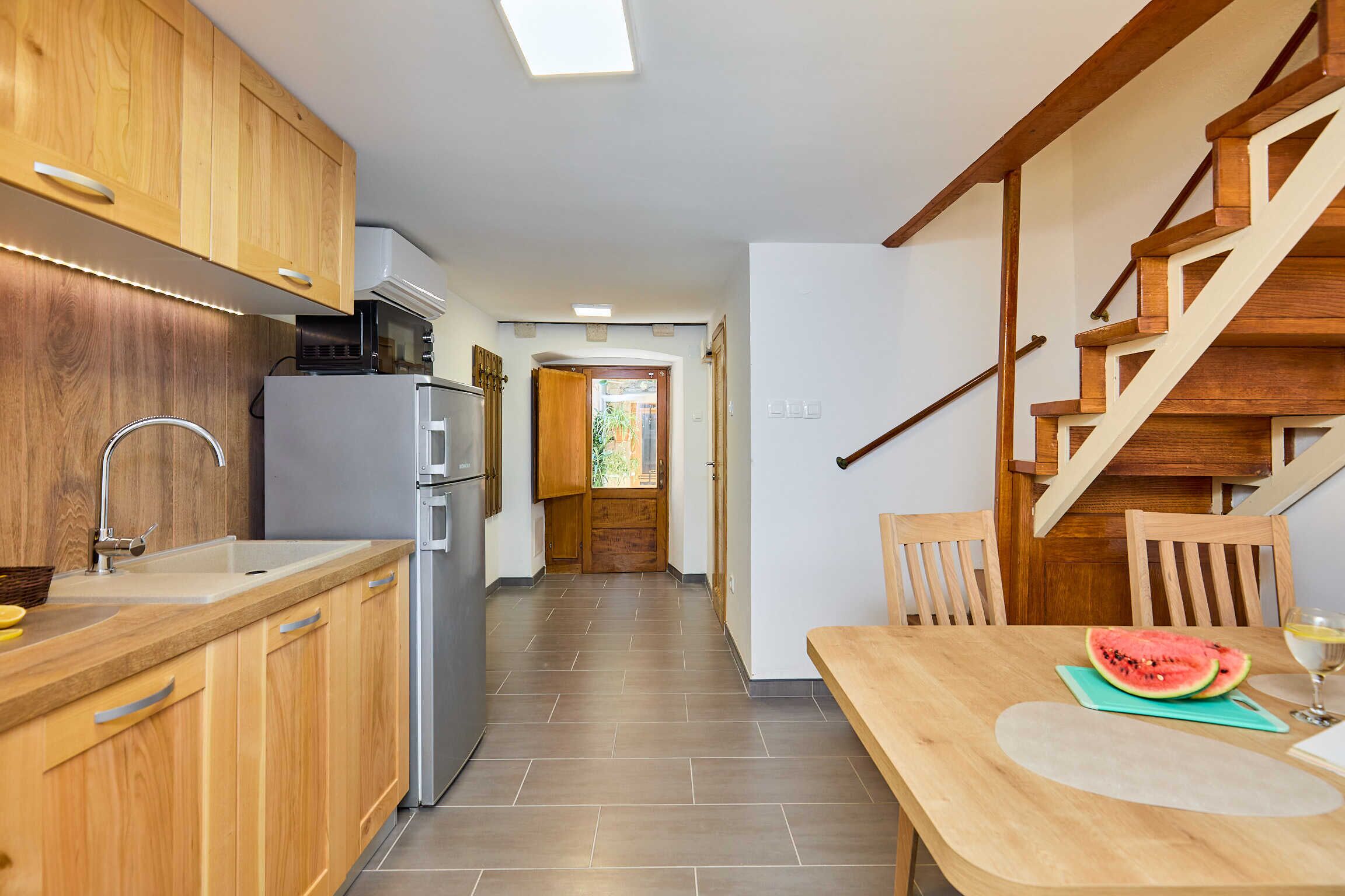 Una cocina con armarios de madera, un refrigerador y un comedor con mesa y sillas.