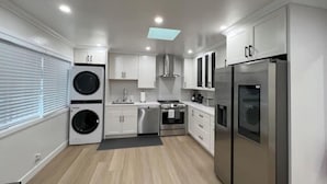 Een moderne keuken met witte kastjes, een roestvrijstalen koelkast, een inbouwoven en een wasmachine.