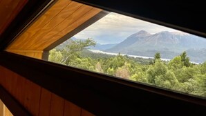 Un tragaluz con vista a un paisaje montañoso y un cuerpo de agua.