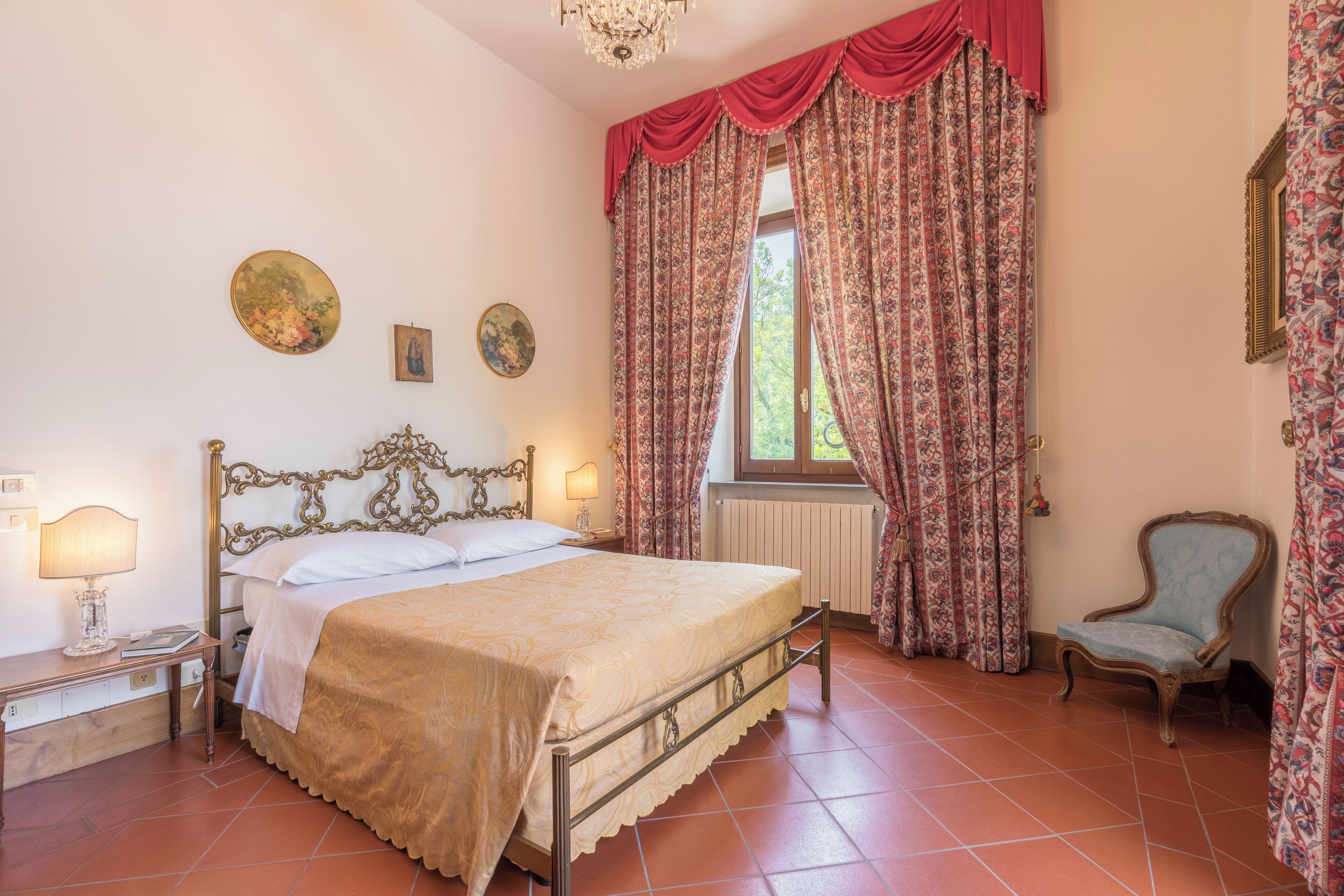 A bedroom with a four-poster bed, a chair, and a window with curtains.