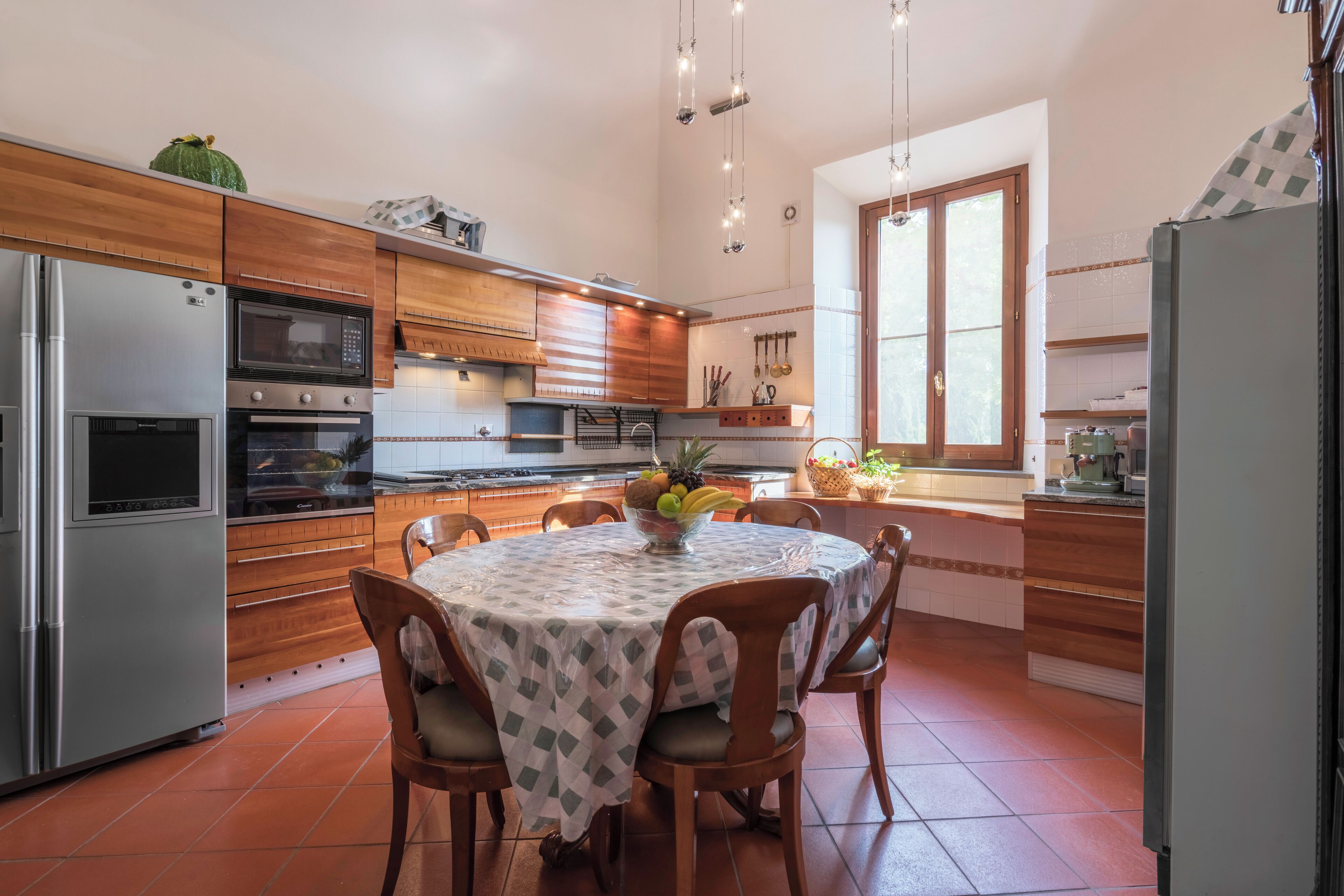 A modern kitchen with wooden cabinets, stainless steel appliances, and a dining area with a table set for four.