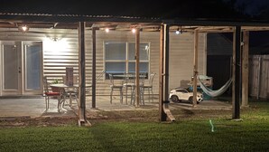 A covered patio area with a table and chairs, a hammock, and a toy car. - Charming home with Oak Tree lined streets in the heart of Lake Charles. (Lake Charles)