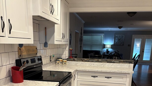 A modern kitchen with white cabinetry, a black stove, and a marble countertop. - Charming home with Oak Tree lined streets in the heart of Lake Charles. (Lake Charles)