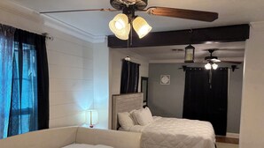 A hotel room with two beds, a ceiling fan, and a nightstand with a lamp. - Charming home with Oak Tree lined streets in the heart of Lake Charles. (Lake Charles)