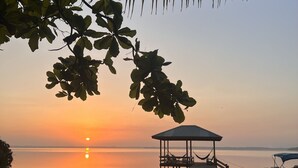Une jetée en bois menant à un belvédère abrité, situé au bord d’un lac paisible, au coucher du soleil.