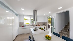 A modern kitchen with white cabinetry, a central island, and a stainless steel range hood.