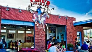 Un edificio de ladrillo con un letrero que dice “PHIL’S ICE CREAM HOUSE” y una escultura de un caballo sobre la entrada.