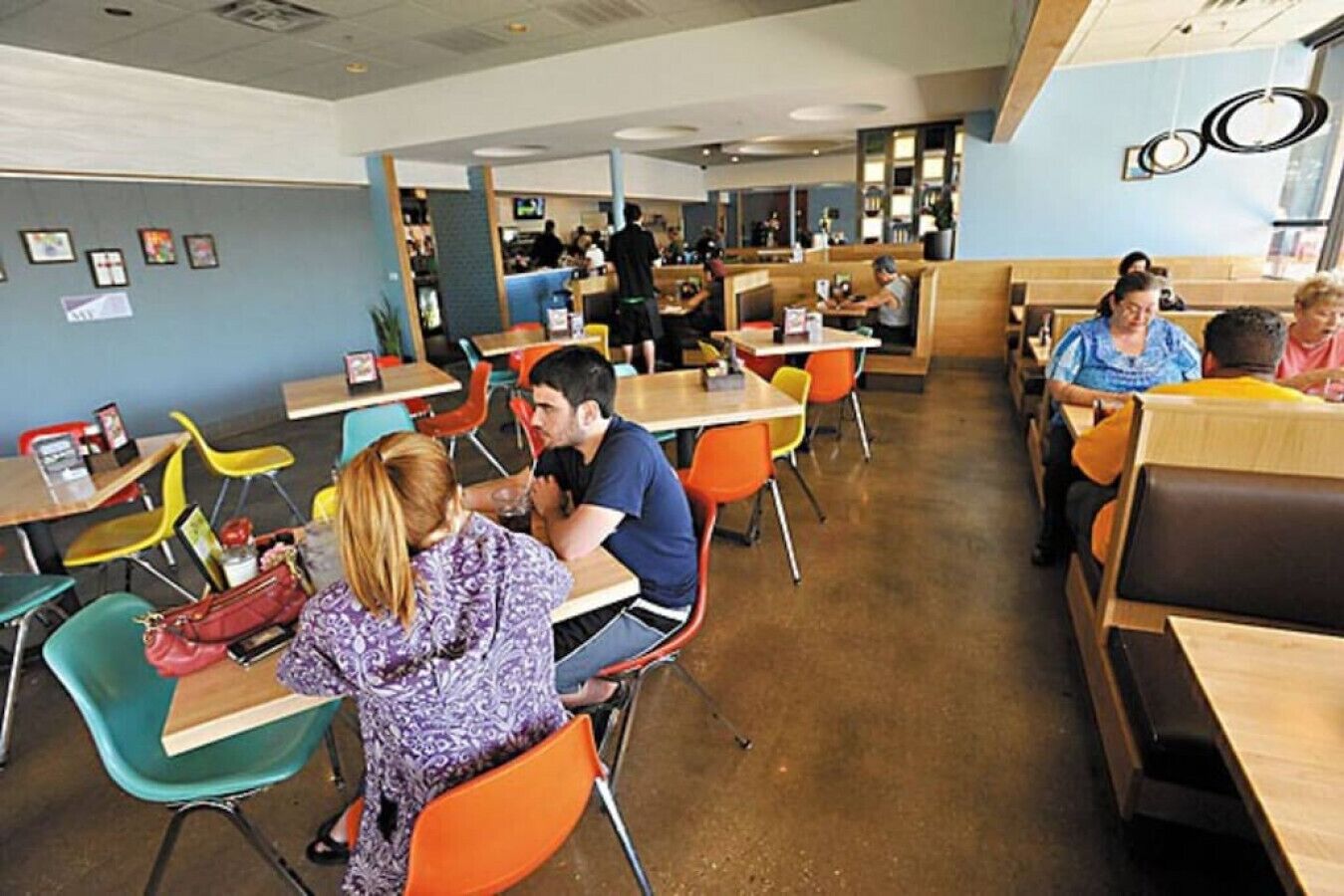 Une cafétéria avec des tables et des chaises, dont certaines sont occupées.
