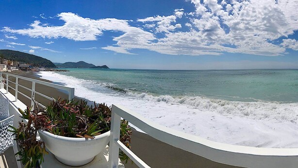 A balcony with a view of the ocean, a white railing, and a potted plant. - AED Home   (Lavagna)