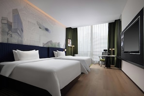 Habitación de hotel con dos camas, un escritorio, una silla, un televisor y un ventanal con cortinas.