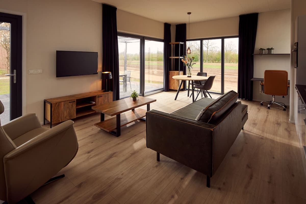 A modern living room with a sofa, a coffee table, a TV, and a dining area with a table and chairs.