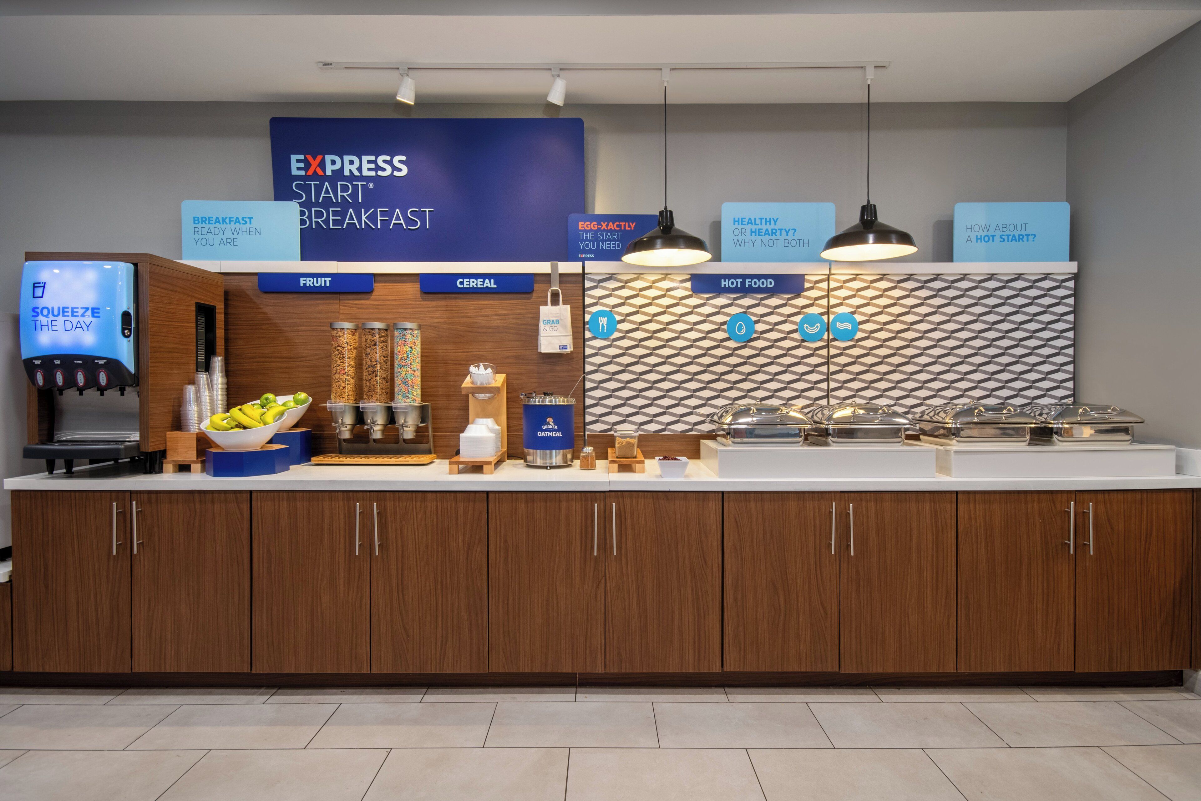 Un espace réservé au petit-déjeuner, avec une enseigne bleue indiquant « EXPRESS START » et proposant divers choix alimentaires, comme des céréales, des fruits et des plats chauds.