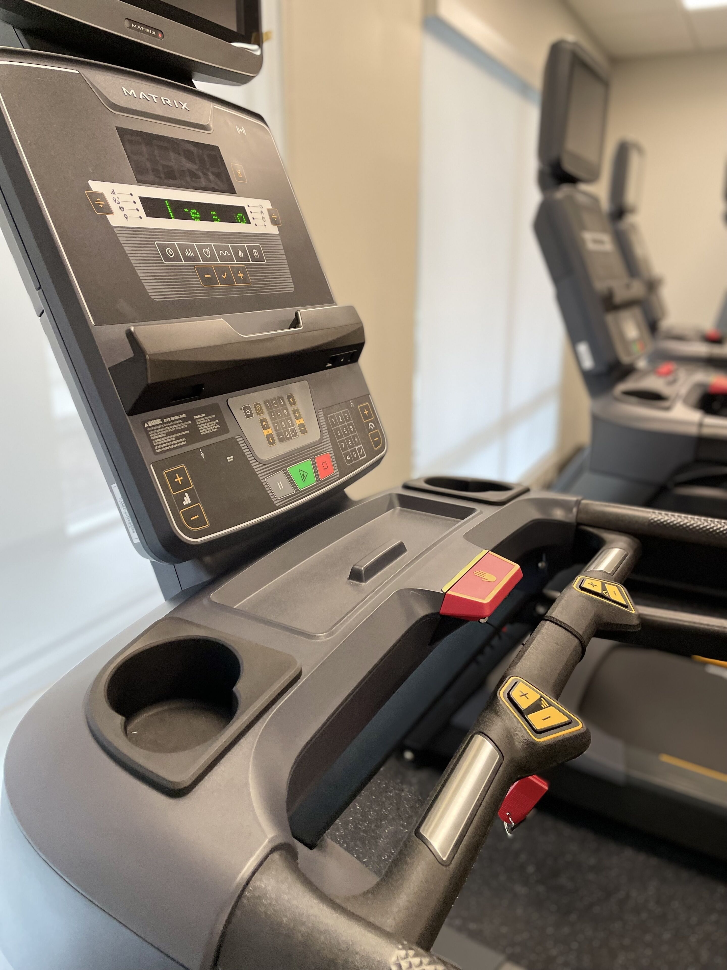 Primer plano de un asiento de avión con panel de control, que incluye una pantalla digital y varios botones.
