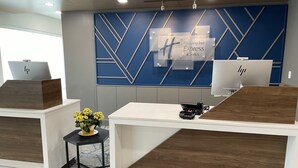 A reception desk with a modern design, featuring a logo for Holiday Inn Express & Suites. - Holiday Inn Express & Suites Muskegon - Grand Haven by IHG (Muskegon)