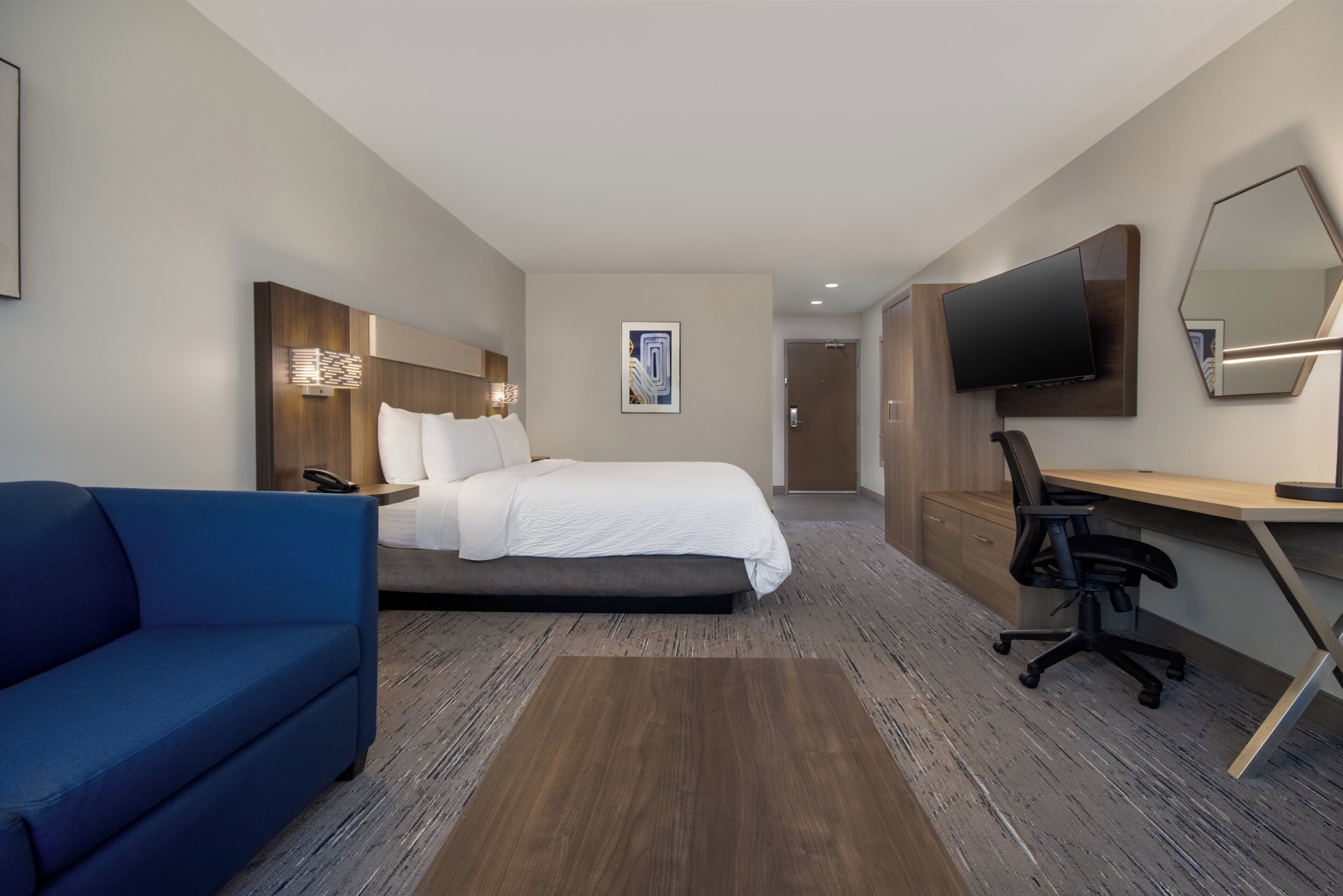 Une chambre d’hôtel équipée d’un lit, d’un bureau, d’une chaise, d’une télévision et d’un canapé.