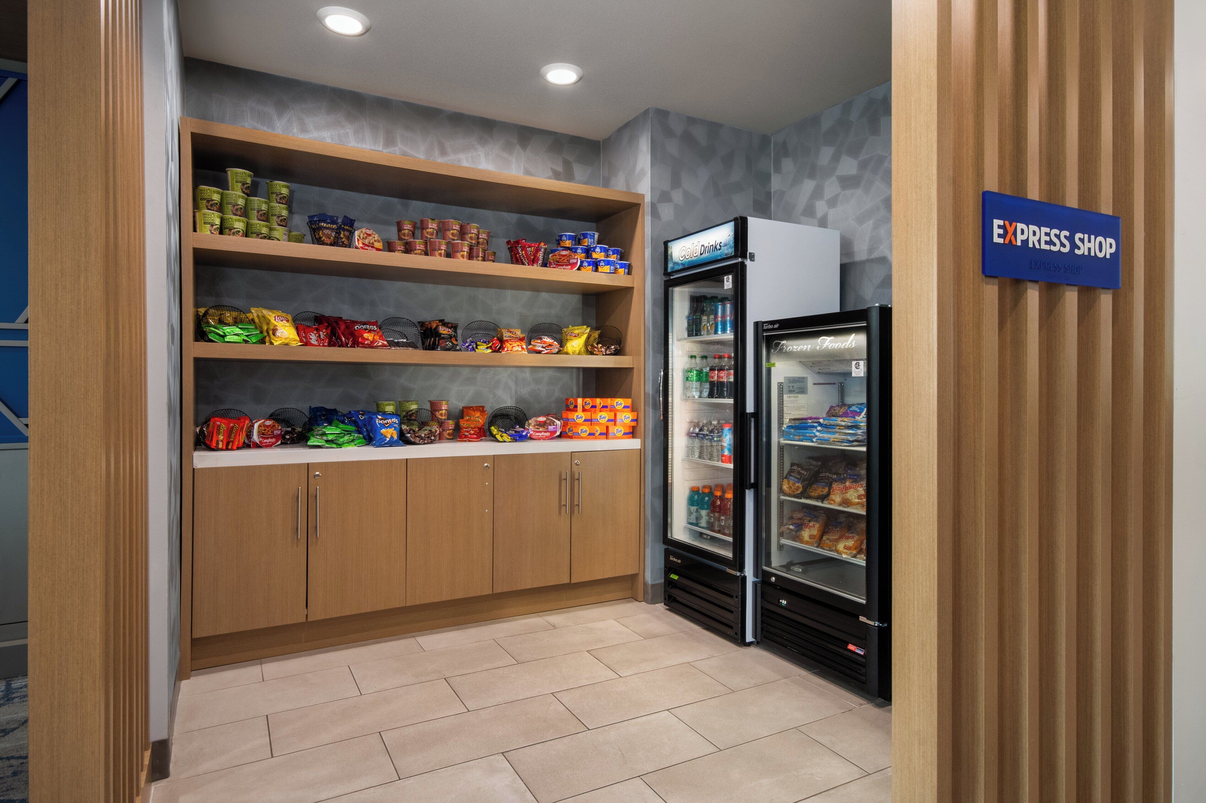 A snack area with shelves stocked with various snacks and a refrigerator.