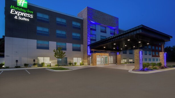 A Holiday Inn Express & Suites building with a modern design, featuring a large sign, a covered entrance, and a parking lot. - Holiday Inn Express & Suites Muskegon - Grand Haven by IHG (Muskegon)