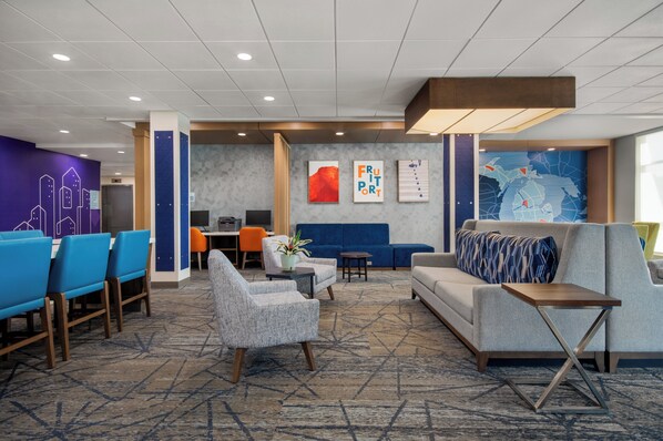 A modern lobby with seating areas, a reception desk, and artwork on the walls.