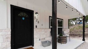 Un bâtiment blanc avec une porte noire, portant le numéro 528, et un porche décoré de guirlandes lumineuses.