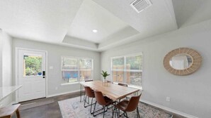 Un coin repas avec une table et des chaises en bois, un tapis à motifs et un miroir rond accroché au mur.