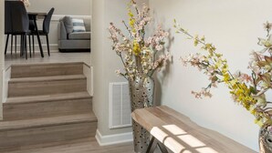 Un intérieur moderne avec un escalier menant à un espace repas, un banc et des éléments décoratifs muraux.