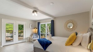Une chambre avec un grand lit, une vue sur l’extérieur grâce à une porte coulissante, une petite table avec une chaise et une lampe.