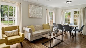 Un salon moderne comprenant un canapé, des fauteuils, une table basse et un coin repas avec des chaises et une table.