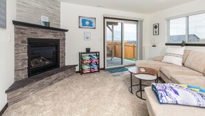 A living room with a fireplace, a sofa, a coffee table, and a sliding glass door leading to a patio.