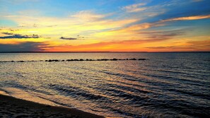 Une plage avec une mer calme et un coucher de soleil.