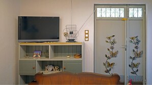 Una sala de estar con un televisor sobre un mueble bajo, una estantería, un adorno de pared y una puerta decorada con motivos de mariposas.