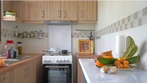 Una cocina con armarios de madera, estufa y encimera con frutas y verduras.