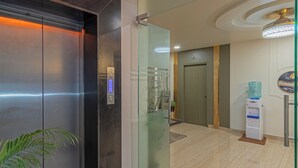 An elevator with a digital display, a glass partition, a water dispenser, and a door with a decorative panel. - Treebo Raghavendra Tranquil Inn Bellandur (Bengaluru)