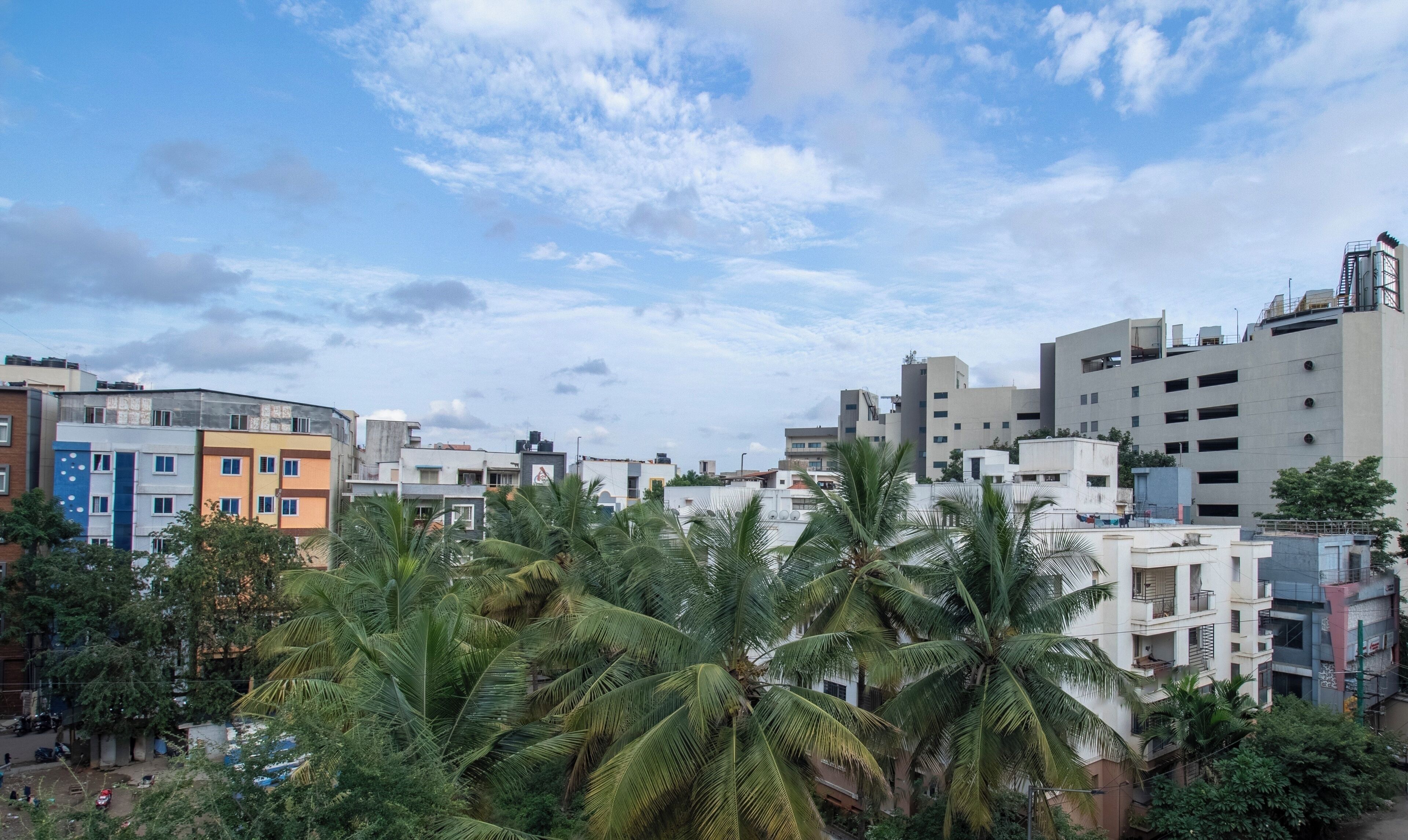 A residential area with multi-story buildings, some with balconies, and palm trees in the foreground.