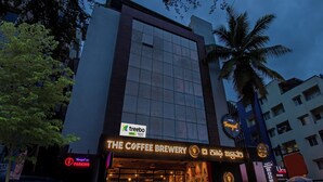 A building with a sign for 'The Coffee Brewery' and 'Tranquil Inn' parking. - Treebo Raghavendra Tranquil Inn Bellandur (Bengaluru)