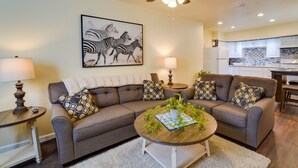 A living room with a sectional sofa, a coffee table with a plant, and a kitchen in the background. - Sunny California Retreat w/ Pool Access & Patio! (Shasta Lake)
