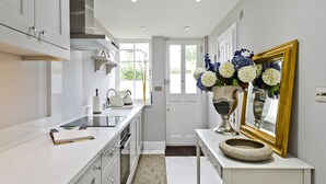 A modern kitchen with white cabinetry, a built-in oven, a sink, and a window with a view of greenery.