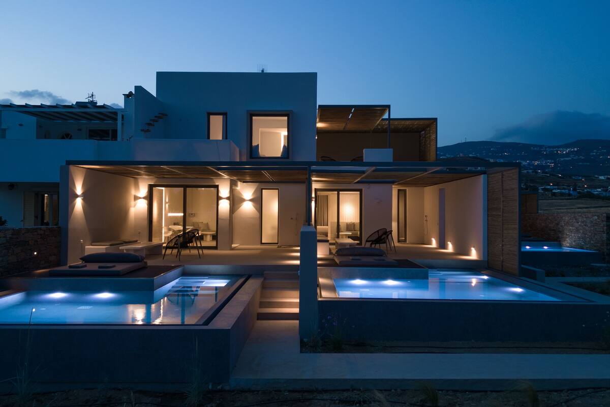 Een modern huis met twee verdiepingen, een buitenzwembad, een overdekt terras en uitzicht op het omliggende landschap.
