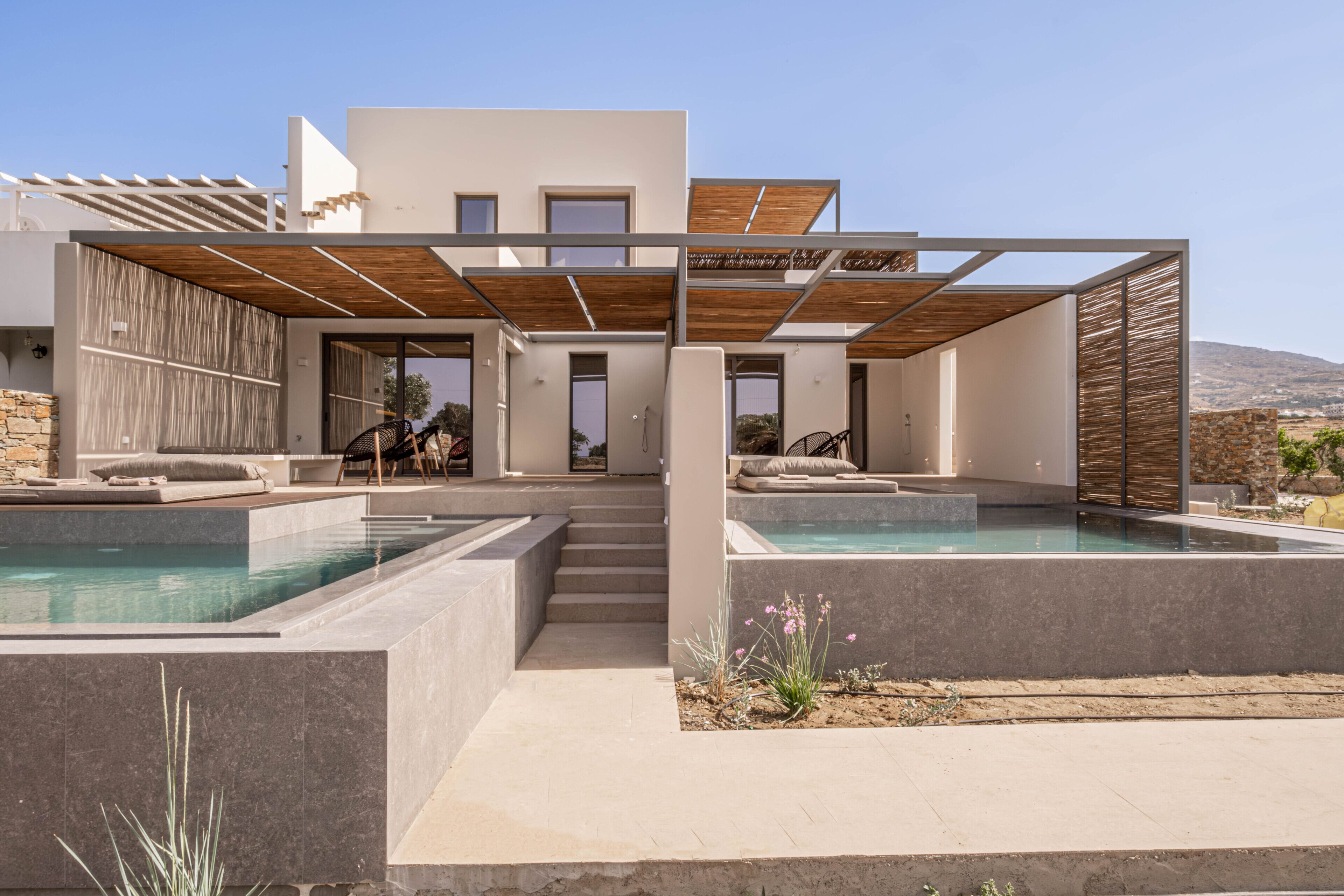 Une maison moderne dotée d’une piscine, d’un espace salon extérieur et offrant une vue sur le paysage.