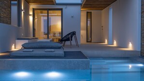 Un espace piscine extérieur moderne, comprenant une chaise longue avec des coussins, une petite table et une chaise.