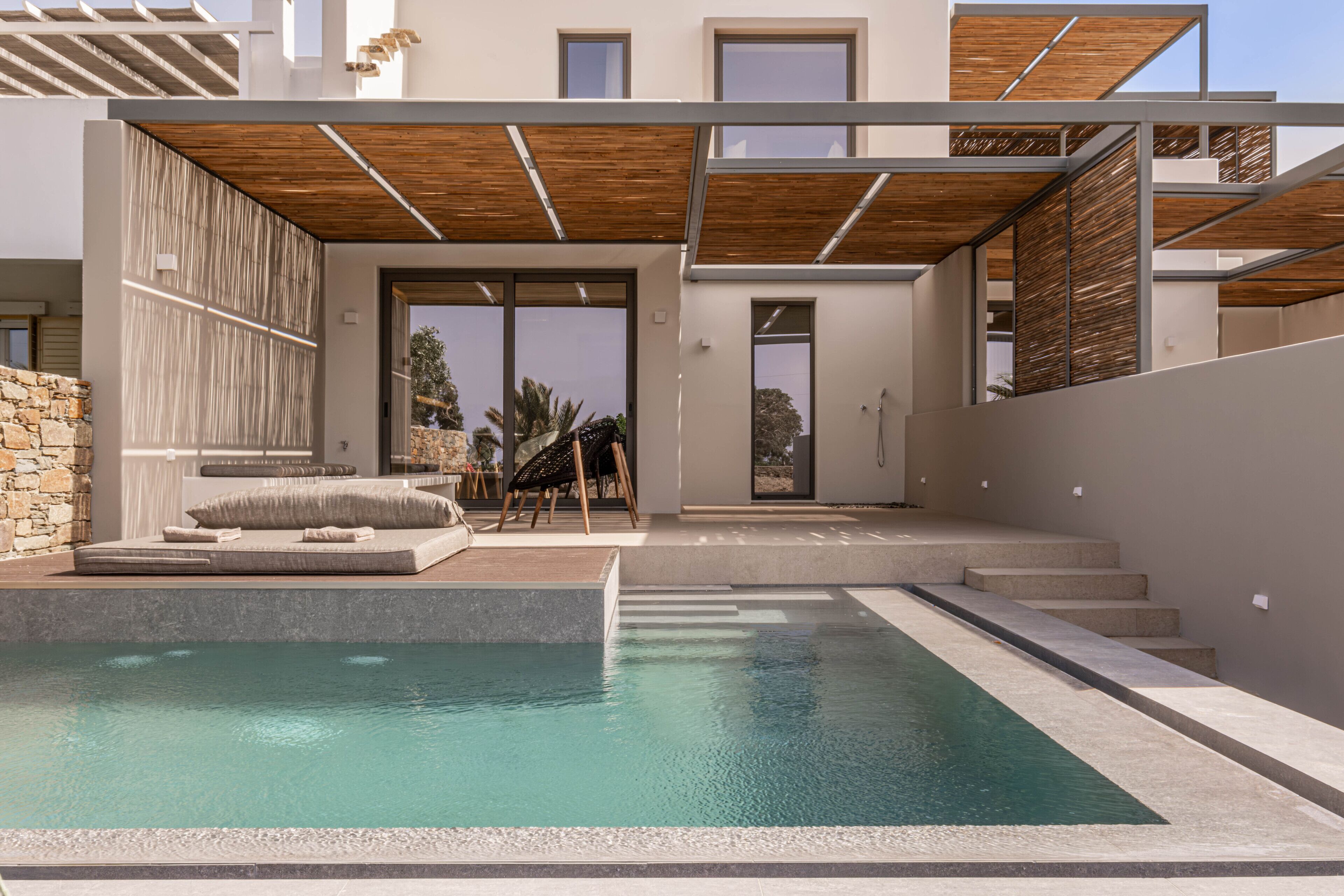 Ein modernes Haus mit Swimmingpool, Steinmauer und Holzterrasse.