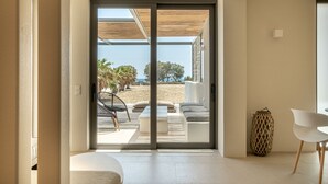 Un intérieur moderne avec une porte-fenêtre coulissante donnant sur un balcon aménagé avec des sièges et offrant une vue sur la plage.