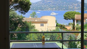 Ein Balkon mit Meerblick, ein Gebäude mit Ziegeldach und eine Flasche auf dem Tisch.