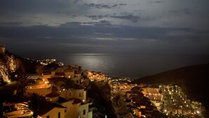 A coastal town at night with a visible moon, buildings with warm lighting, and a calm sea. - Montecristo los Cabos Villa de Lujo, Descansa con Vista Espectacular del Océano (Cabo San Lucas)