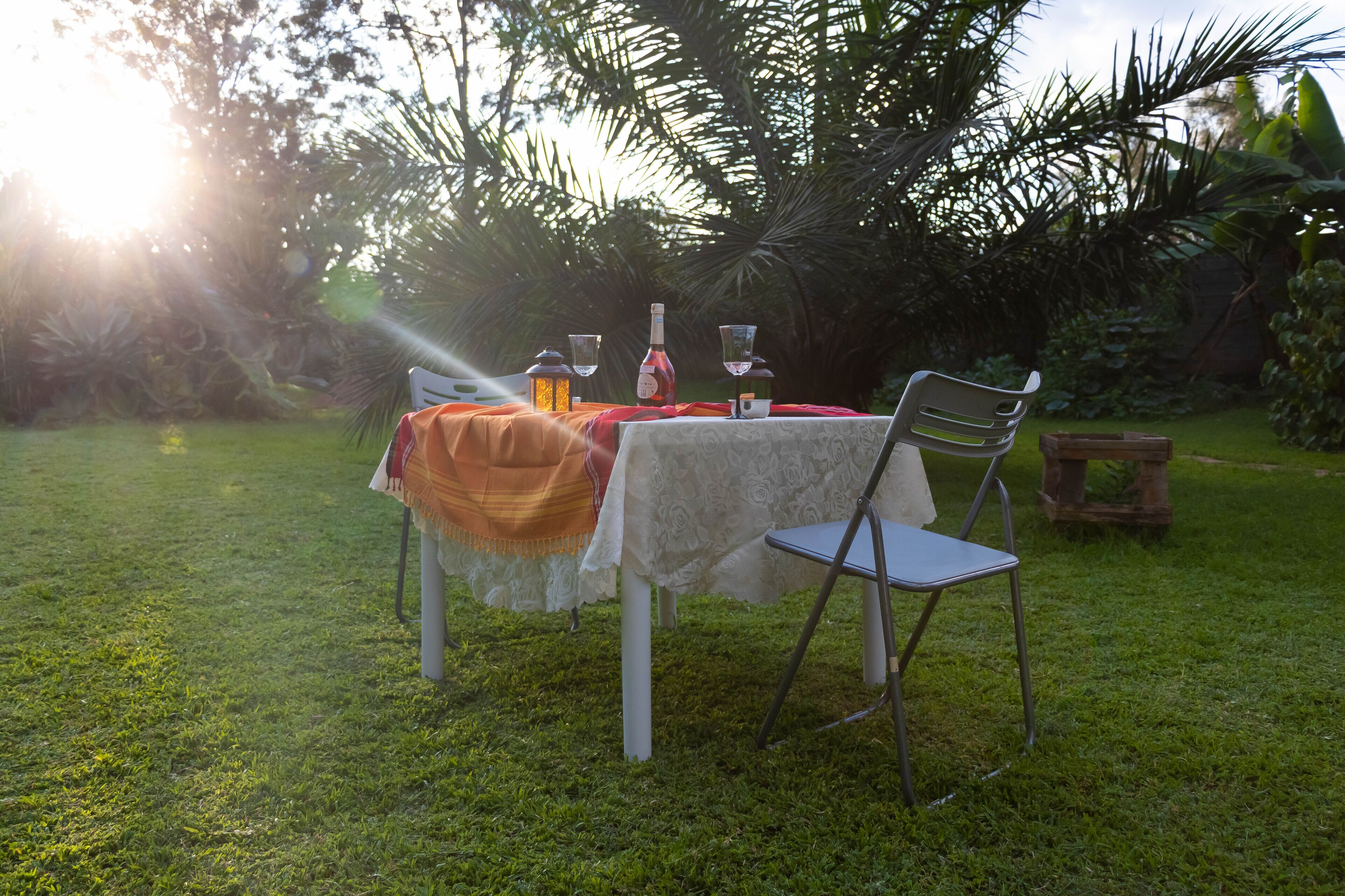 An outdoor dining area with a table set for two, surrounded by lush greenery.
