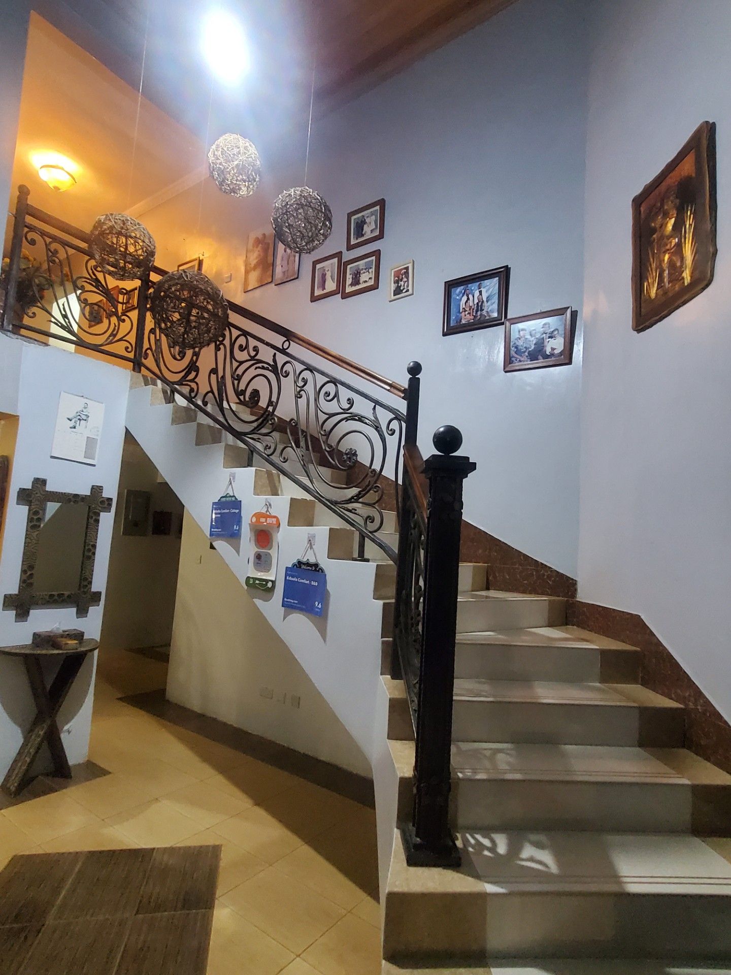 A staircase with ornate metal railings and a series of framed pictures on the walls.