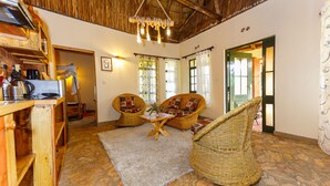 A cozy room with wicker furniture, a coffee machine, and a rustic ceiling. - Edaala Comfort (Nairobi)