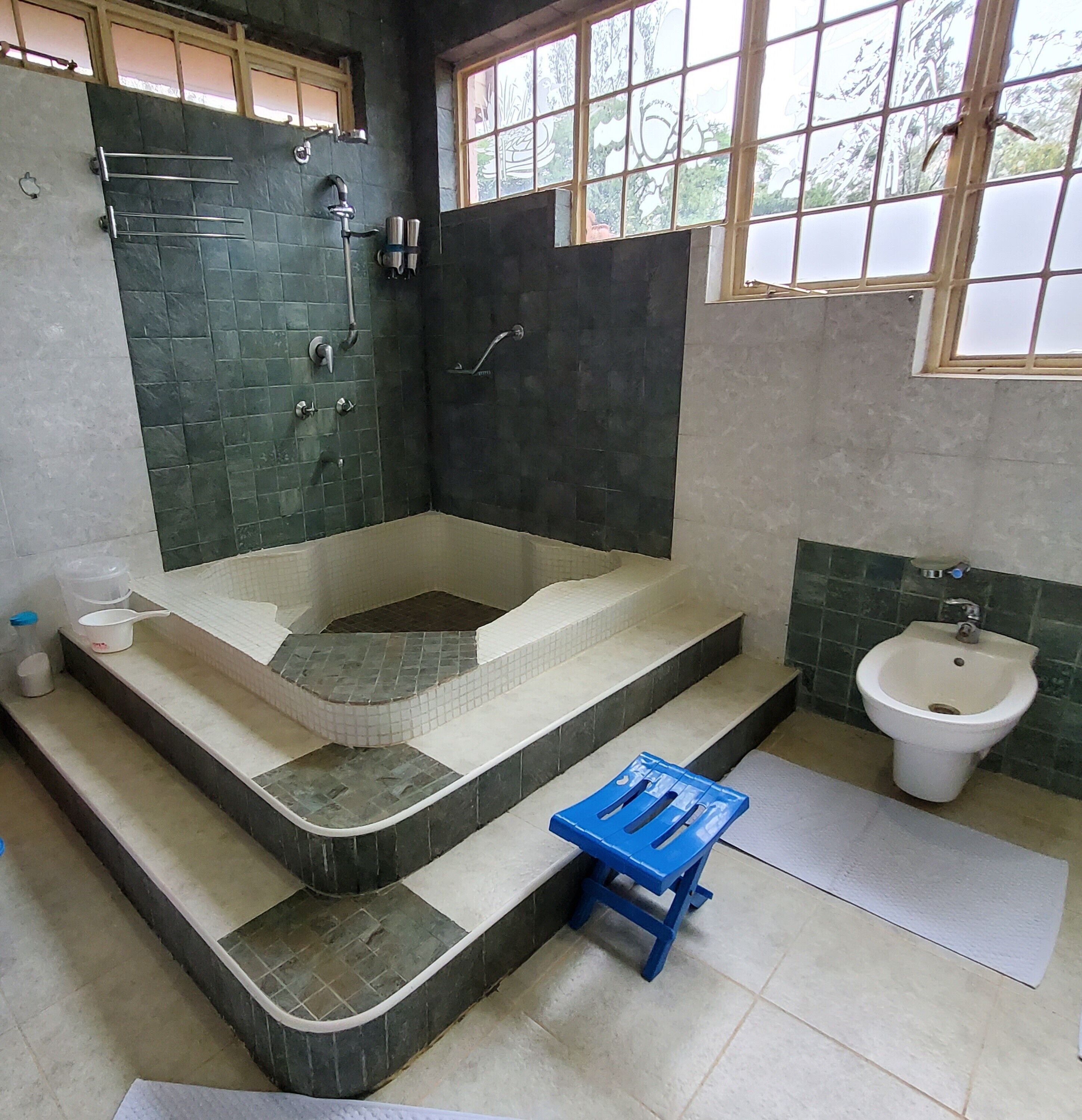 Un baño con una bañera grande, un bidé y un taburete pequeño azul.