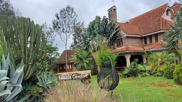 A large, rustic house with a red-tiled roof and a sign reading "Edala Comfort". - Edaala Comfort (Nairobi)
